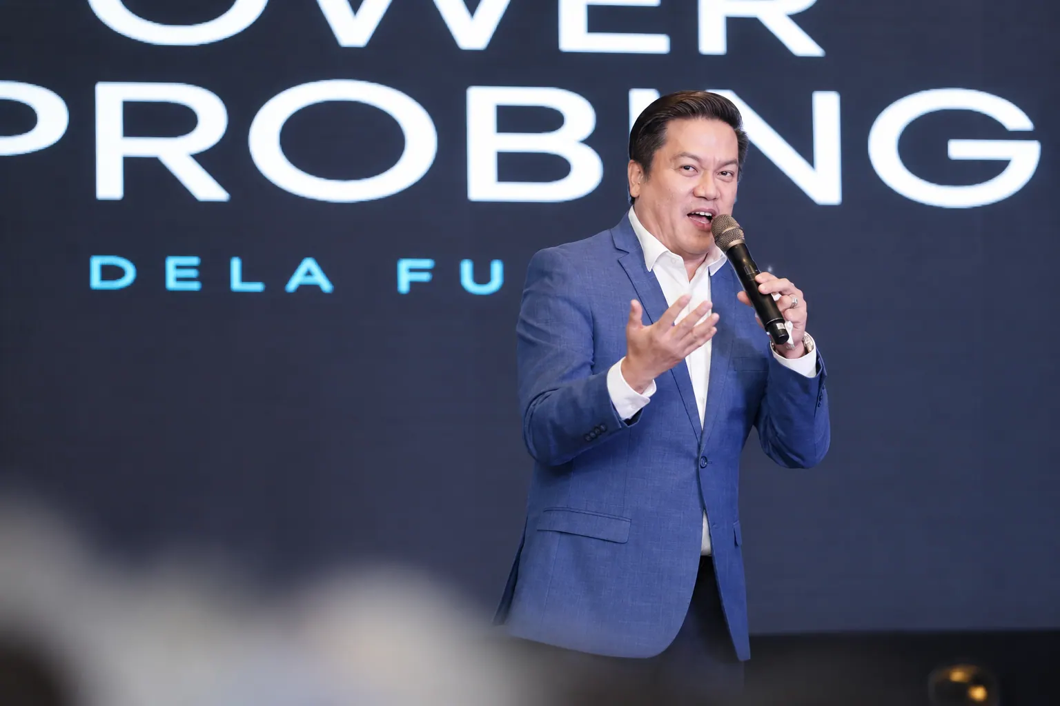 Coach AJ speaking on stage with a microphone